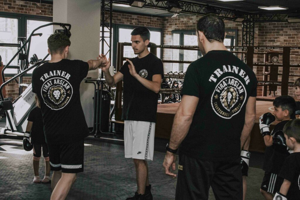 Trainer zeigt Jugendlichem Boxtechnik
